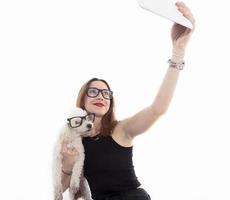 menina bonita tira uma selfie com seu cachorro no fundo branco foto