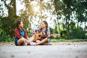 duas garotas relaxando e tocando violão foto