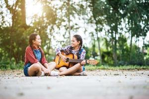 duas garotas relaxando e tocando violão foto