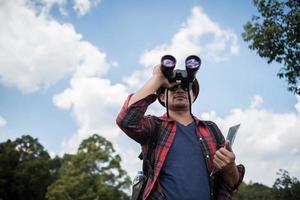 jovem com binóculos na floresta foto