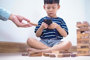 crianças asiáticas na era das redes sociais que se concentram em telefones ou tablets. não se preocupam com o meio ambiente e têm problemas oculares. conceito de crianças viciadas em videogame foto