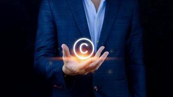 empresário segurando o ícone de direitos autorais, patentes e direitos e leis de proteção de propriedade intelectual. com símbolo do símbolo copyright.copyright do autor. foto