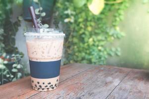 bolha de café gelado com copo de plástico para viagem na mesa de madeira no jardim foto