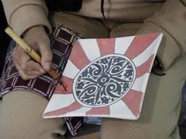 artesão marroquino pintando e decorando produtos cerâmicos na fábrica de cerâmica em fez, marrocos foto