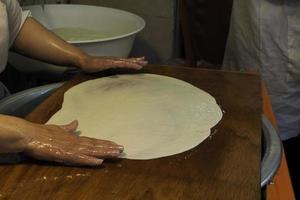 mãos de mulher amassando massa em uma mesa oleosa cozinhando rghayf tradicional ou msemen, um pão marroquino tradicional em fes medina foto