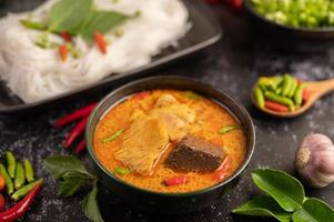 curry de frango em uma xícara preta com macarrão de arroz foto
