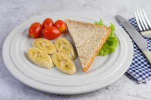pão com banana e tomate em um prato branco