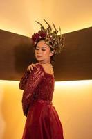 mulher asiática em vestido vermelho posando com uma coroa de ouro na cabeça foto