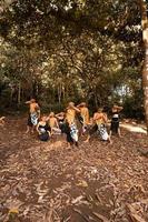 dança javanesa em trajes dourados enquanto usam uma pose de maquiagem juntos perto das folhas marrons foto