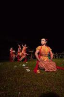 um grupo de dançarinos indonésios se apresentando no palco com um lenço vermelho e um vestido laranja tradicional dentro do festival foto