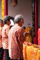 cidade de bandung, indonésia, 2022 - o velho traz as oferendas ao altar enquanto reza com os monges foto