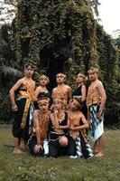 um grupo de balineses posa junto com um rosto feliz enquanto veste trajes dourados após a apresentação foto