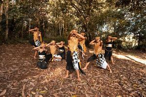 dançarinas balinesas com trajes dourados e calças listradas dançam junto com as folhas marrons mortas no quintal foto