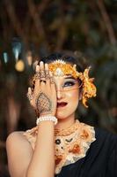 mulher asiática com maquiagem cobrindo o rosto com a mão durante a maquiagem e usando uma coroa de ouro e tiara de ouro foto