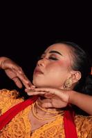 rosto aproximado de uma mulher indonésia com maquiagem e um vestido laranja enquanto usava uma joia de ouro no pescoço foto