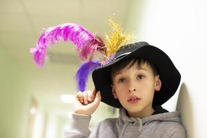 menino com um chapéu de teatro com penas. jovem artista do estúdio de teatro. foto