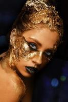 pele dourada da arte da moda. menina modelo com maquiagem profissional brilhante glamourosa dourada festiva. joias de ouro, bijuterias, acessórios. belo corpo metálico dourado, lábios e pele negra.