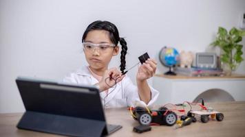 estudantes asiáticos aprendem em casa codificando carros robôs e cabos de placas eletrônicas em haste, vapor, matemática engenharia ciência tecnologia código de computador em robótica para conceitos infantis. foto