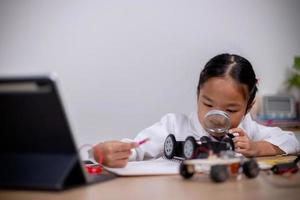 estudantes asiáticos aprendem em casa codificando carros robôs e cabos de placas eletrônicas em haste, vapor, matemática engenharia ciência tecnologia código de computador em robótica para conceitos infantis. foto