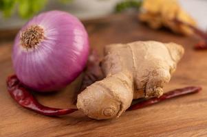 cebola roxa, pimenta e gengibre em uma mesa de madeira foto