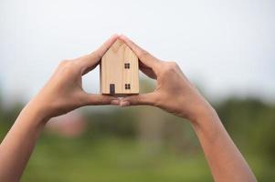 novo conceito de casa - família jovem com modelo em escala de casa dos sonhos nas mãos foto