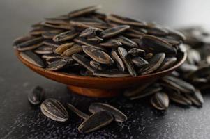 sementes de girassol em uma tigela de madeira na superfície preta foto