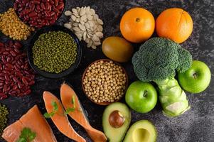 legumes, brócolis, frutas e salmão em um fundo de cimento preto foto