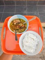 uma tigela de sopa e um prato de arroz em um prato largo laranja foto