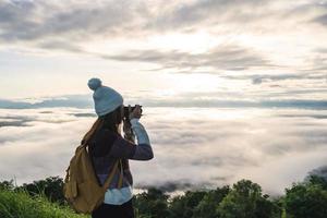 jovem viajante tomando um belo nascer do sol e o mar de névoa na montanha pela manhã, conceito de estilo de vida de viagem foto