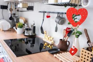 o interior da cozinha da casa é decorado com corações vermelhos para o dia dos namorados. decoração na mesa, fogão, utensílios, clima festivo em ninho familiar foto