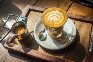 café com latte art na bandeja de madeira ao sol