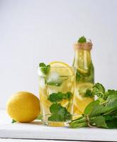 bebida refrescante de verão limonada com limões, folhas de hortelã, limão em um copo foto