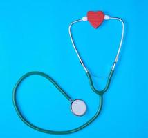 estetoscópio médico verde e coração de madeira vermelho foto