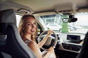 olha para trás. motorista feminina dentro do automóvel moderno. testando carro novo foto