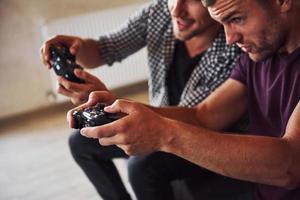 grupo de amigos se diverte jogando jogo de console dentro de casa na sala de estar foto