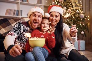 família feliz dentro de casa com chapéus de natal se divertem juntos e comemoram o ano novo foto