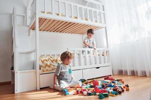 dois meninos se divertem dentro de casa no quarto com conjunto de construção de plástico foto