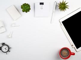 mesa branca com tablet eletrônico, cartões de visita em branco foto