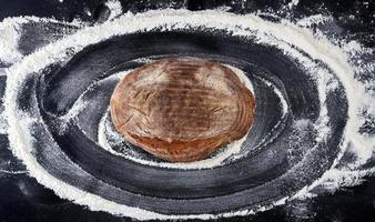 pão assado e farinha de trigo branca espalhada sobre uma mesa preta foto