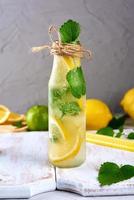 limonada com limões, folhas de hortelã, limão em uma garrafa de vidro foto