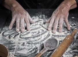 as mãos dos homens mexem a farinha de trigo branca foto