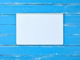 caderno aberto em uma célula em um fundo azul de madeira foto