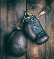 luvas de boxe de couro surradas muito velhas penduradas em um prego foto