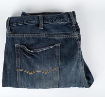 calça jeans masculina azul dobrada em um fundo branco, foto