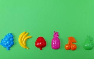 frutas multicoloridas de brinquedos de plástico em um fundo verde foto