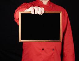 chef de uniforme vermelho segurando uma moldura de madeira vazia foto