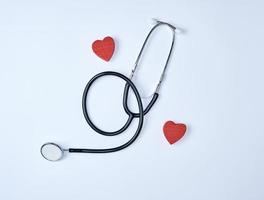 estetoscópio médico preto e dois corações vermelhos de madeira foto
