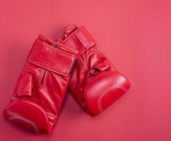 luvas de boxe de couro esporte vermelho sobre um fundo vermelho foto