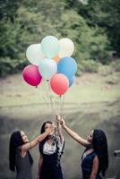 namoradas felizes segurando balões multicoloridos em um parque