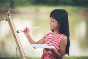 menina artista pintando um quadro no parque foto